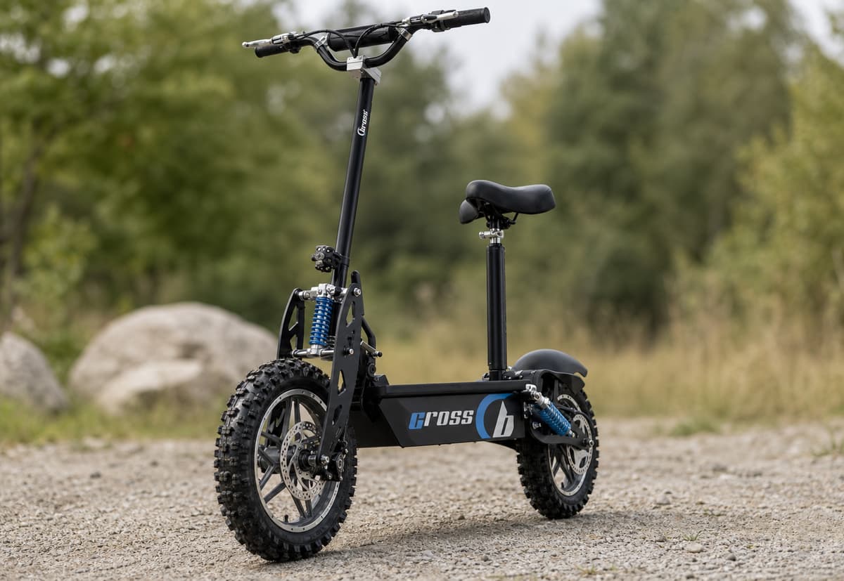 Trottinette électrique tout-terrain dotée d'une selle unique et de pneus à crampons, stationnée de trois quarts sur un sol en gravier stabilisé.